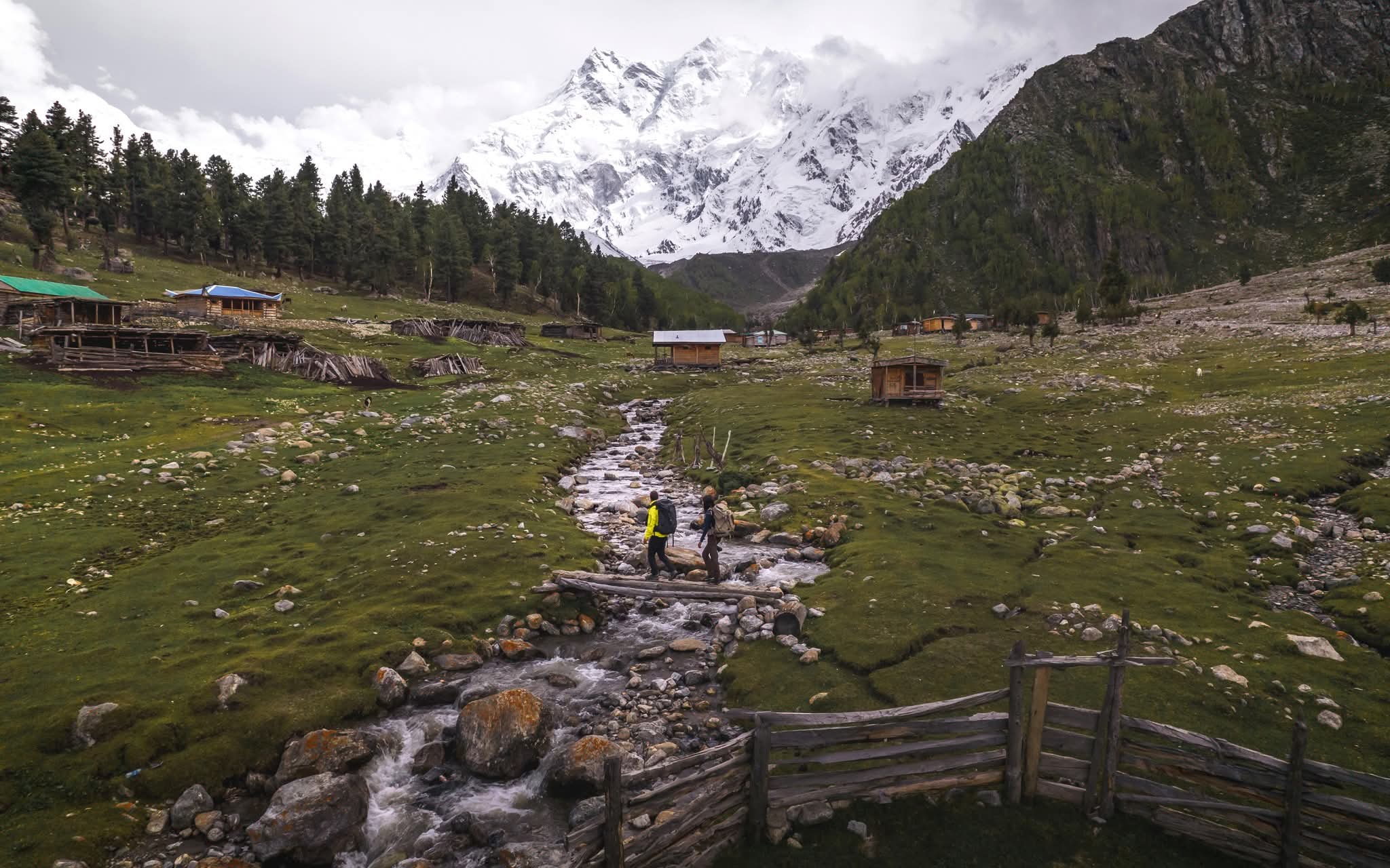 Trekker crossing a wooden bridge in Fairy Meadows beneath Nanga Parbat